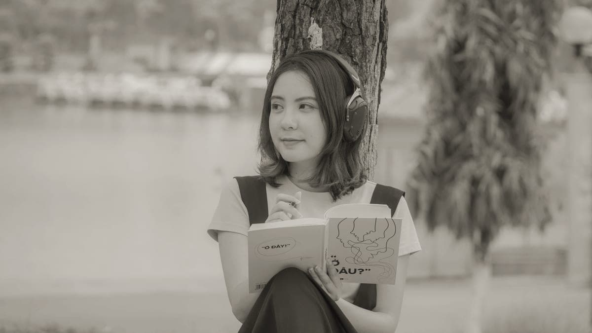 A person listening to an audiobook through headphones outdoors